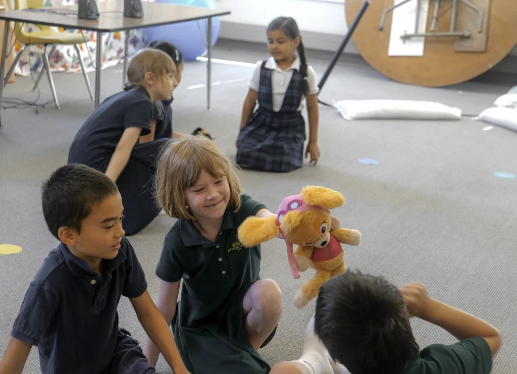 An elementary student holding a stuffed plushie