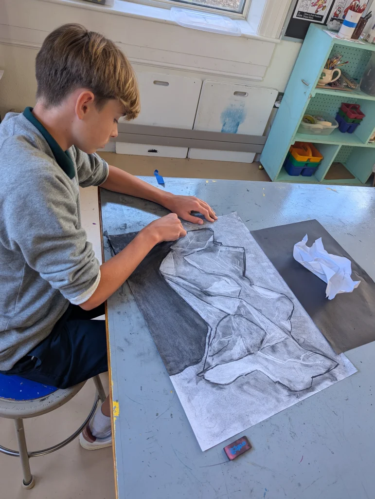 A high school student charcoal drawing in art class