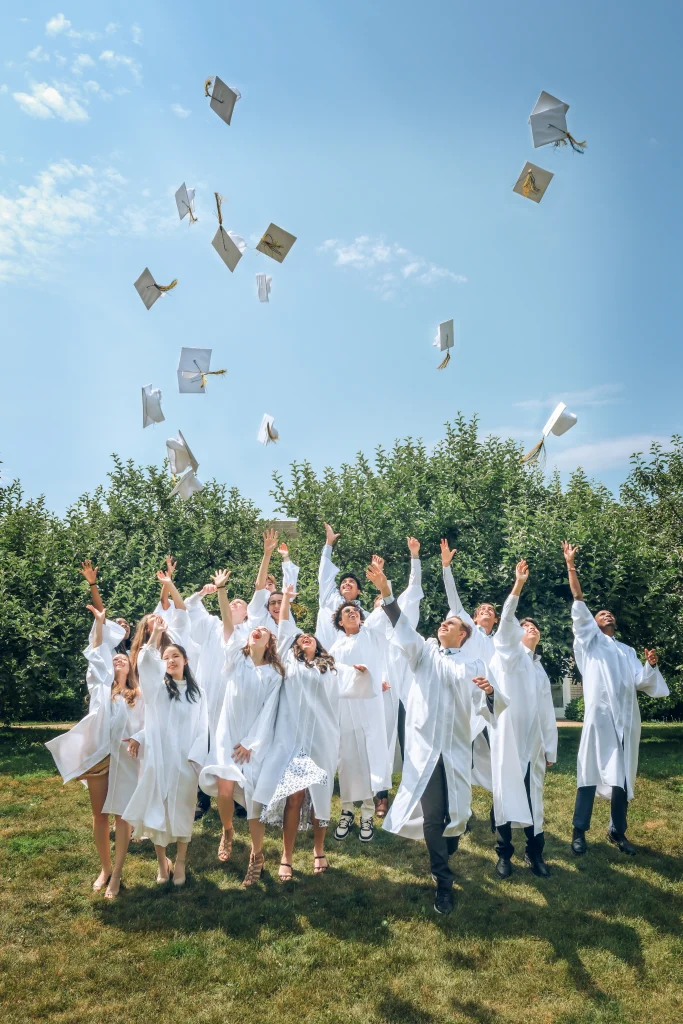 A high school graduate tossing their cap at graduation