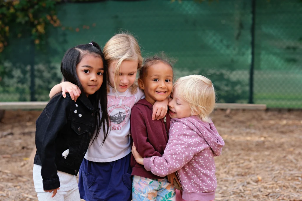 A small group of preschool girls huddled together outside