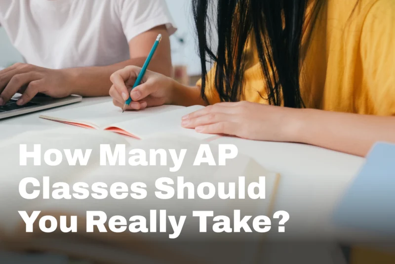 Two students' hands at a desk, one typing on a laptop and one writing in a notebook, with the words "How Many AP Classes Should You Really Take?'